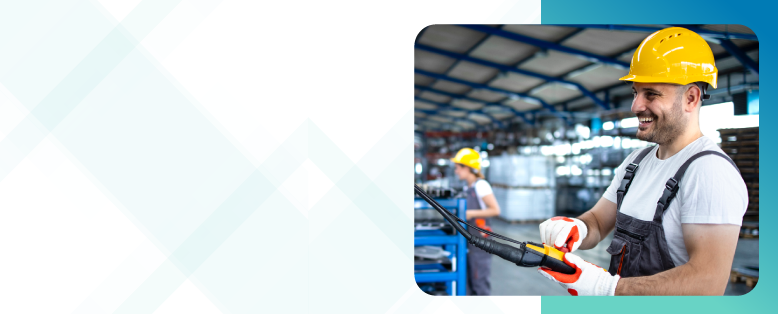Smiling man wearing suspenders and a hard hat works in a factory using cloud ERP for manufacturing