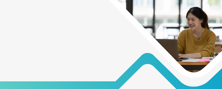 Smiling businesswoman works with non profit finance software on a laptop sitting on a table covered with paperwork