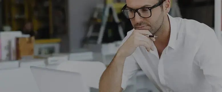 Businessman in glasses holds a pen while attending SAP Business One demo on his laptop